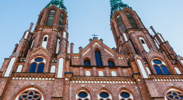 Imponująca ceglana bazylika z dwiema strzelistymi wieżami, ozdobiona oknami i detalami architektonicznymi. Jeden z najpiękniejszych kościołów w Polsce.
