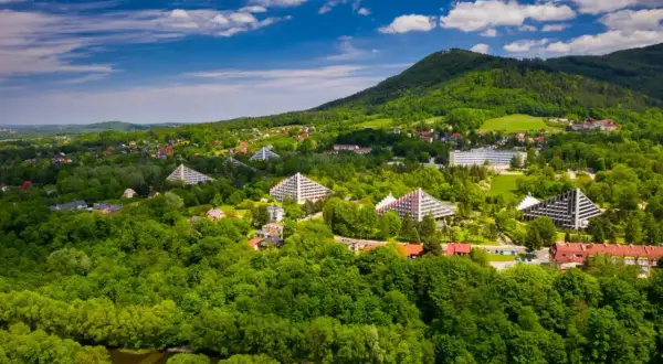 Widok na zielone wzgórza i charakterystyczne, trójkątne budynki sanatoryjne w Ustroniu Śląskim.