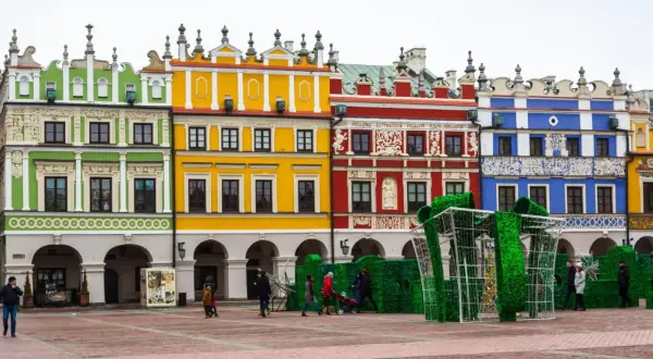Kolorowe kamienice na Rynku w Zamościu, znane z unikatowych zdobień, tworzą malownicze tło dla świątecznej instalacji w kształcie prezentu.