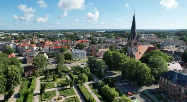 Widok na miasto z lotu ptaka, z dominującą wieżą kościoła i zielonym parkiem. Szczecinek atrakcje zachęcają do spacerów.
