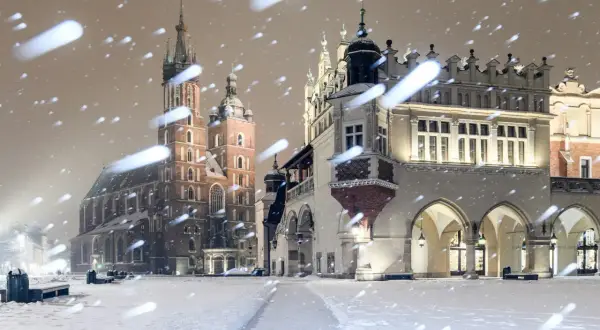 Magiczny krakow zima. Rynek Główny w śnieżnej scenerii, z Kościołem Mariackim i Sukiennicami w tle, podczas nocnych opadów śniegu.