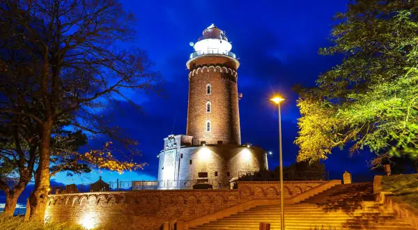 Wieczorem rozświetlone latarnie morskie polska, otoczone drzewami i schodami, tworzą magiczny widok.