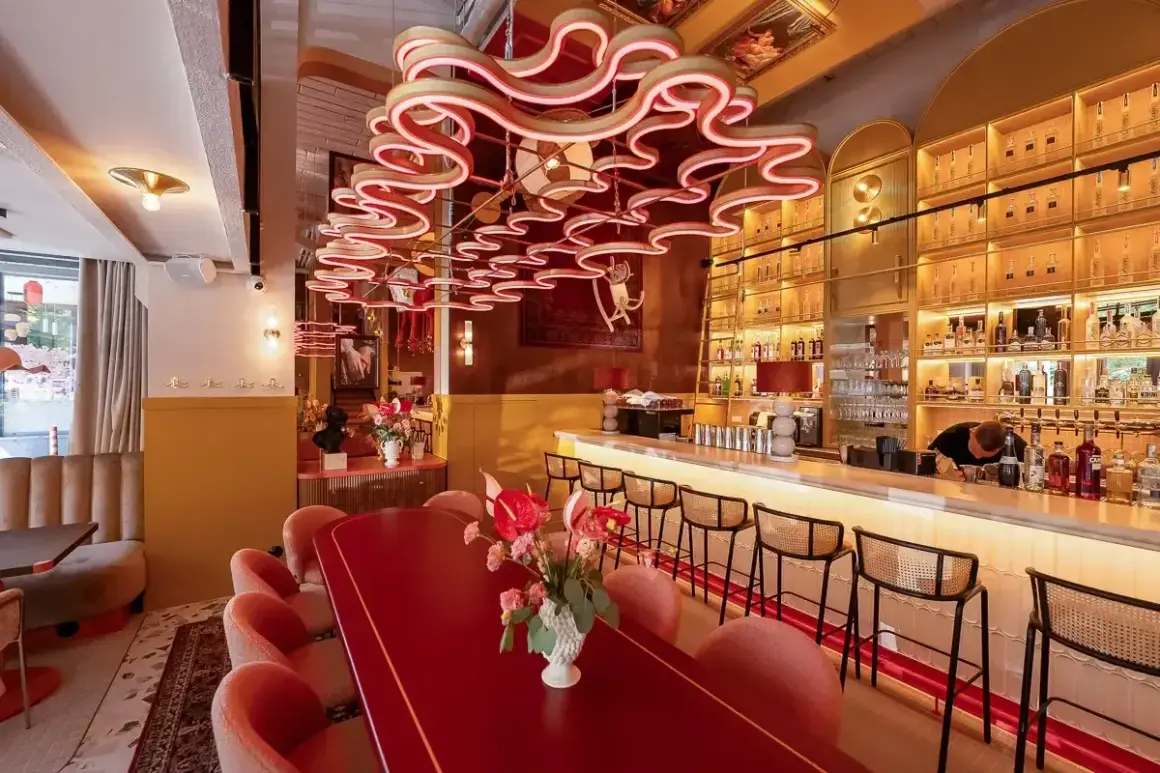 Eleganckie restauracje Kołobrzeg: czerwony stół, różowe fotele i bar z alkoholem.