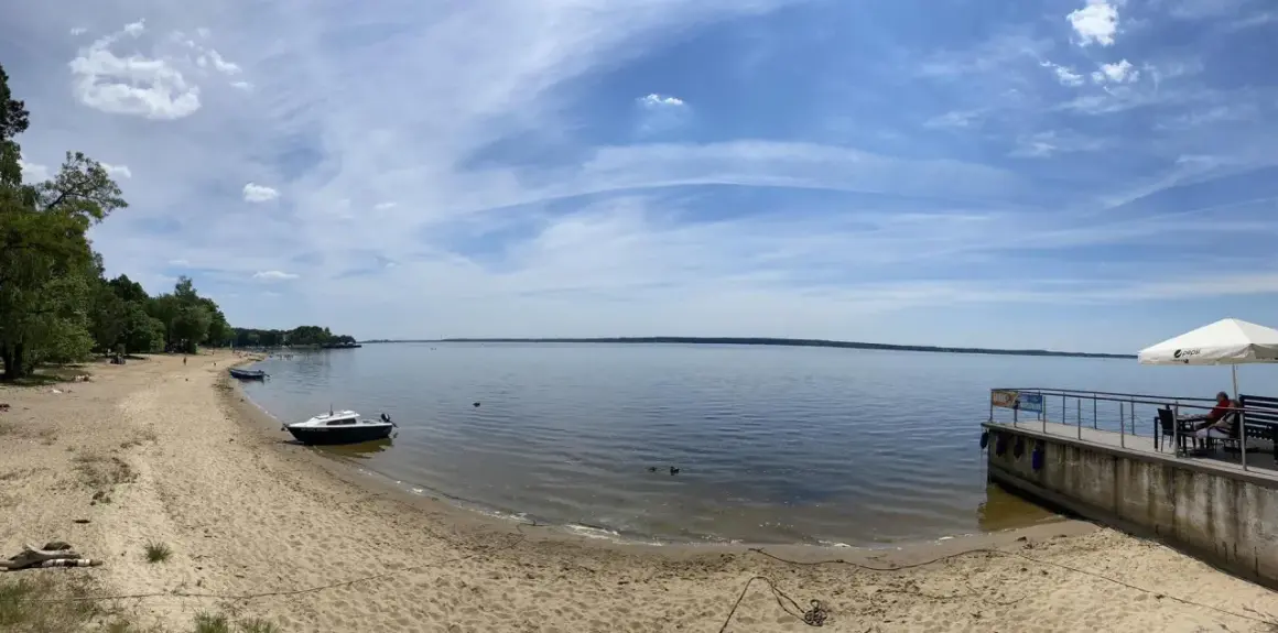 Piękny dzień nad jeziorami opolskimi. Piaszczysta plaża, spokojna woda i błękitne niebo zapraszają do wypoczynku.