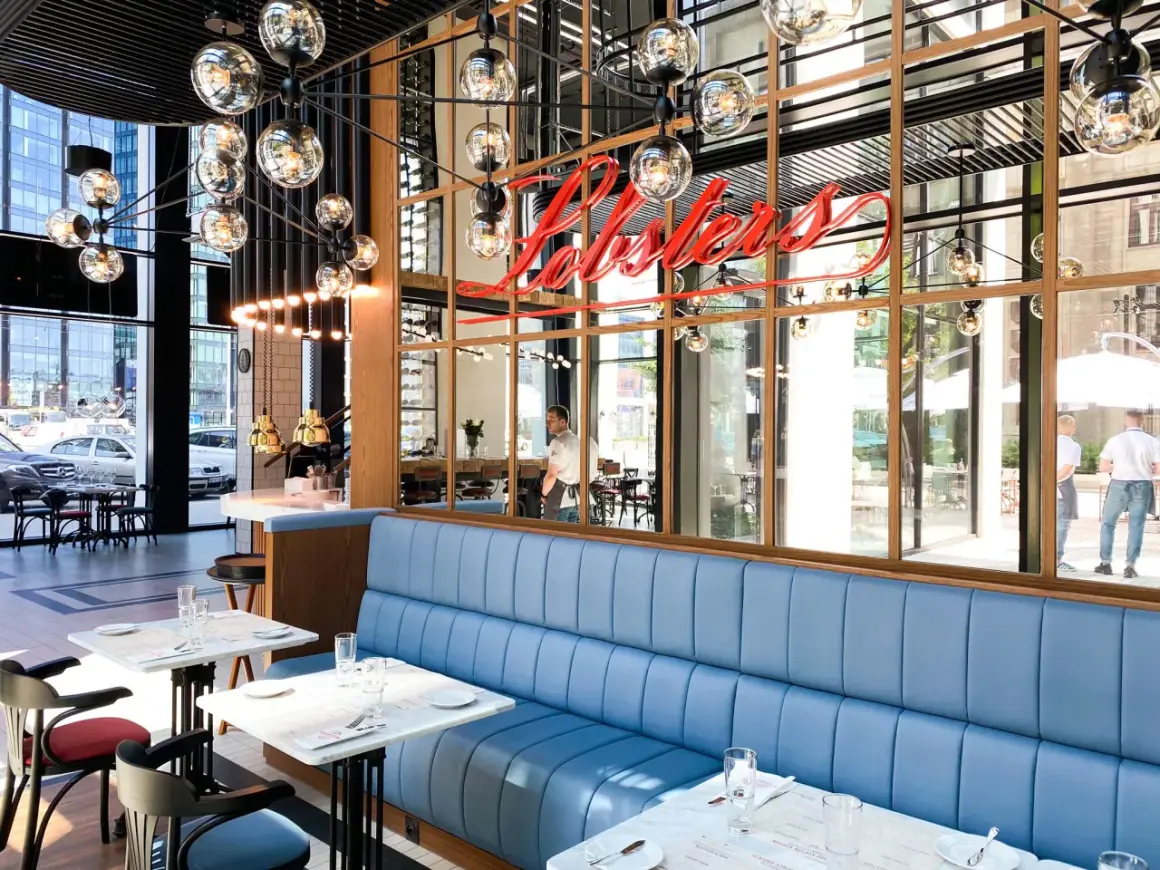 Eleganckie restauracje w Warszawie z niebieskimi kanapami i neonowym napisem "Lobsters".
