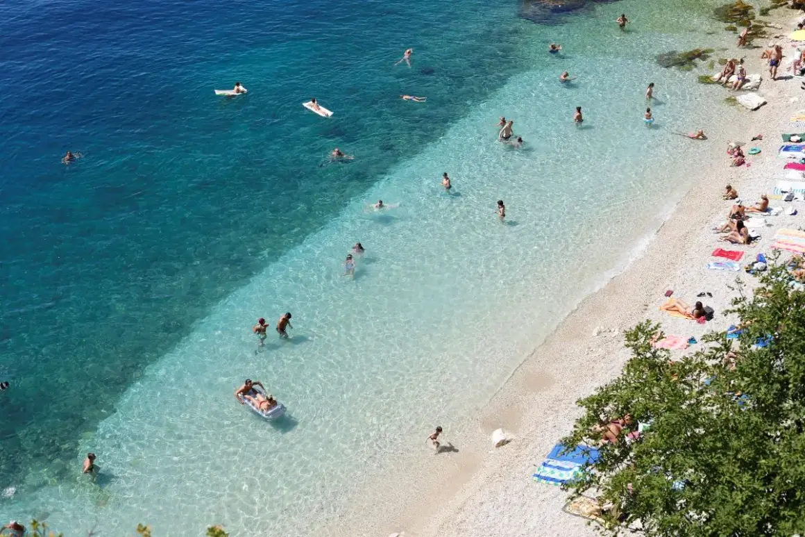 Słoneczne rijeka plaże z turkusową wodą. Ludzie kąpią się, opalają na kamienistej plaży i relaksują na materacach.