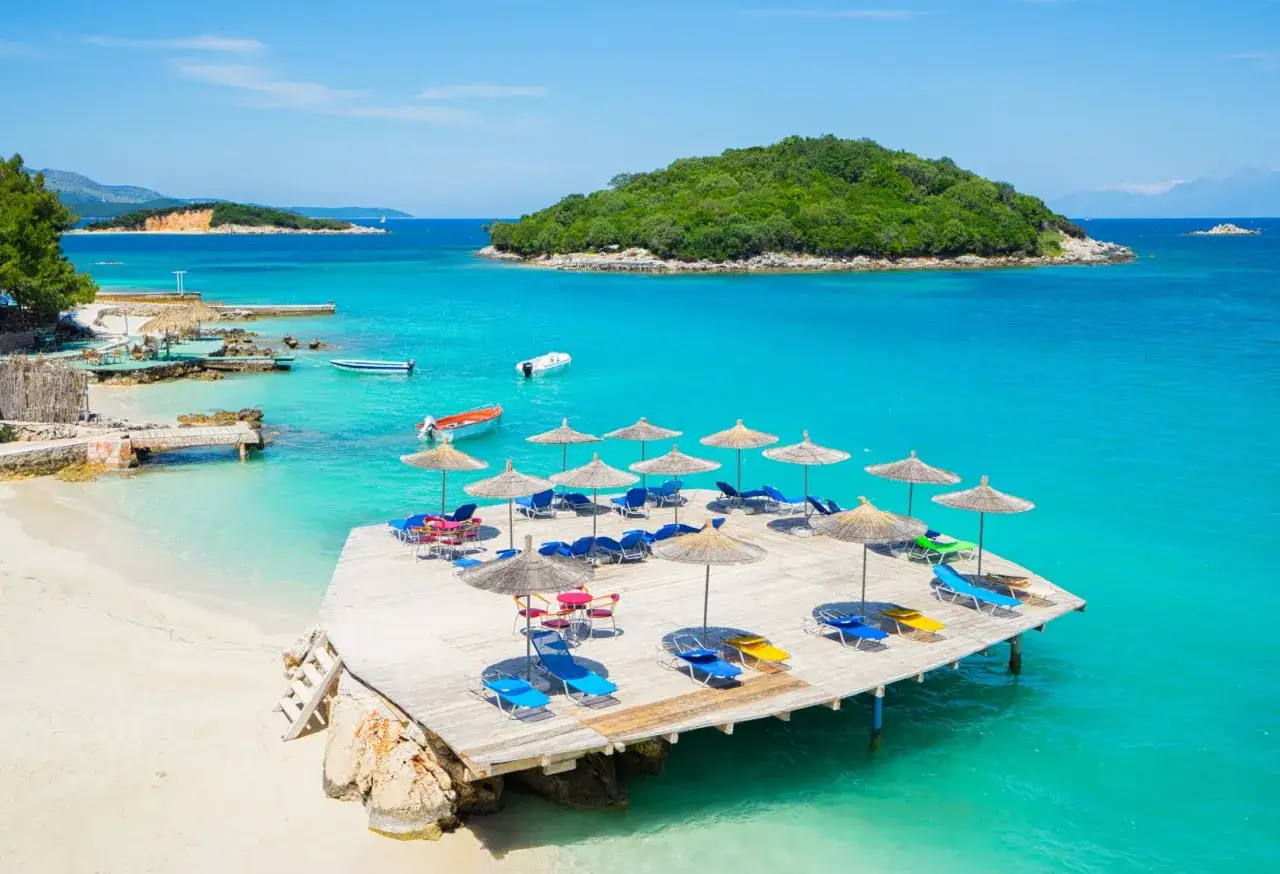 Rajskie albania plaże z turkusową wodą, drewnianym molo, leżakami i parasolami. Idealne miejsce na relaks.