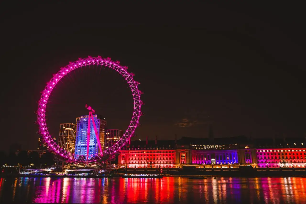 Londyn nocą: London Eye i podświetlone budynki nad Tamizą. Niezapomniane atrakcje Anglii.