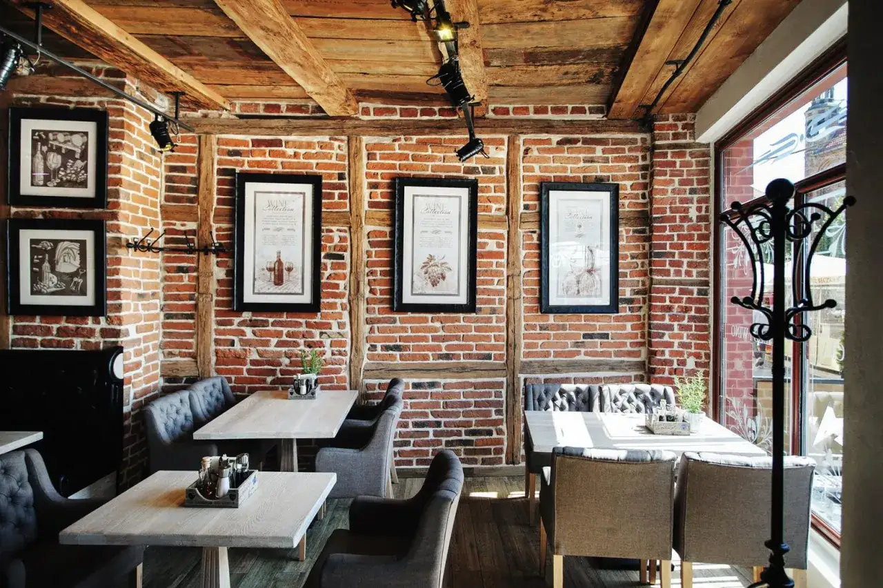Przytulne wnętrze restauracji w Toruniu, gdzie zjeść można w otoczeniu ceglanych ścian i drewnianych belek.
