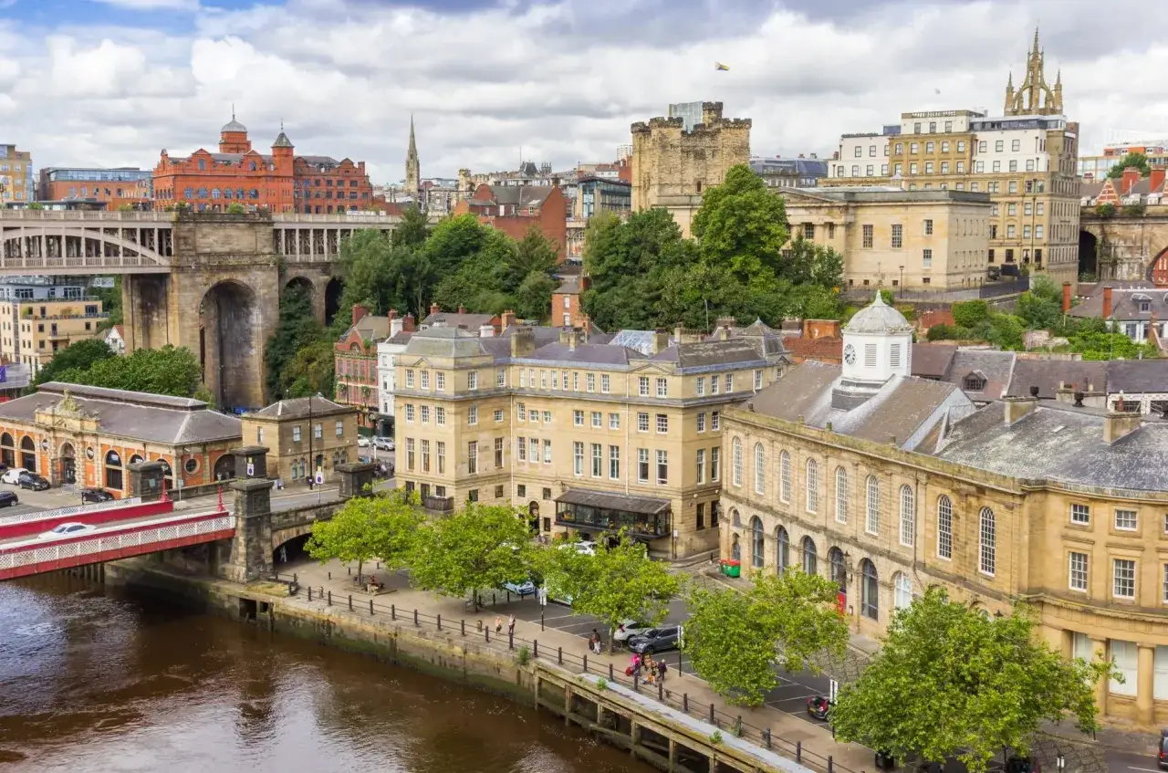 Widok na rzekę i zabytkowe budynki w Anglii. Atrakcje Newcastle, w tym most i zamek, tworzą malowniczy krajobraz.