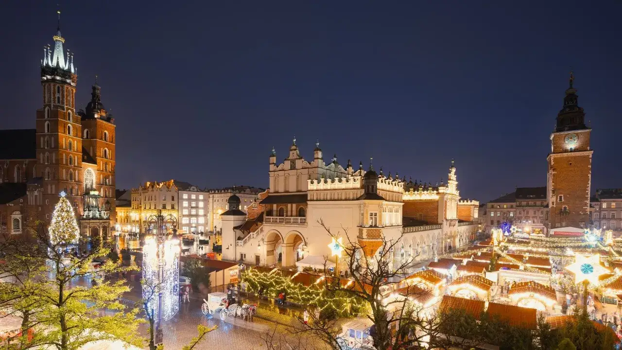 Magiczny krakow zima. Rynek Główny nocą, rozświetlony jarmarkiem bożonarodzeniowym, z Kościołem Mariackim i Sukiennicami w tle.