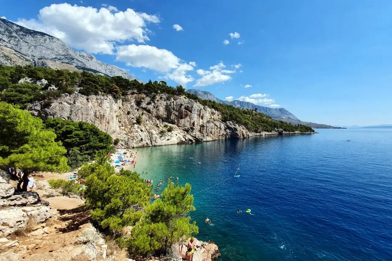 Słoneczna plaża w Makarskiej, skaliste klify, turkusowe morze i zielone sosny. Idealne miejsce na relaks i podziwianie pięknych widoków. Makarska atrakcje zachwycają!