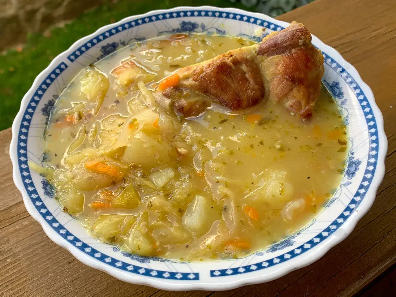 Gęsta zupa z kapusty i ziemniak&oacute;w z kawałkiem mięsa, pachnąca jak domowe jedzenie zakopane w smaku.