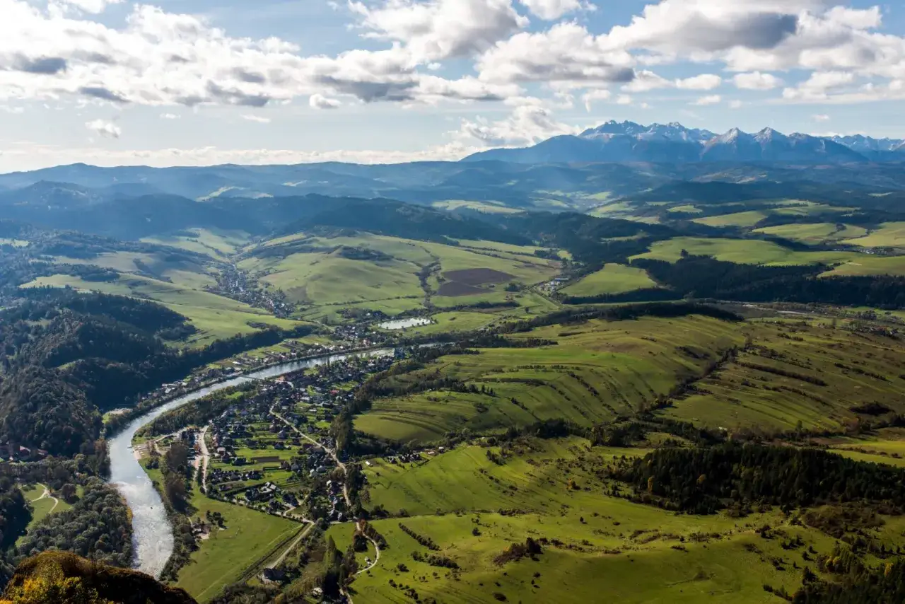 Widok na malowniczą dolinę Dunajca, miasteczko i g&oacute;ry. W oddali widać majestatyczne Tatry, a bliżej zielone wzg&oacute;rza Pienin. Trzy Korony Pieniny wspaniale prezentują się z tej perspektywy.