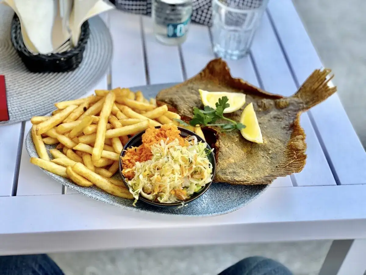Smażona flądra z frytkami i sur&oacute;wką, idealna propozycja w restauracjach Kołobrzeg.