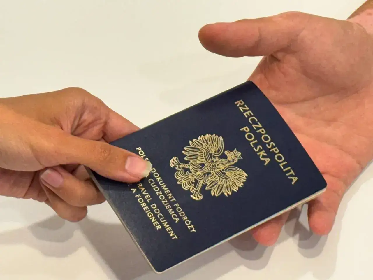 Paszport polski przekazywany z ręki do ręki. Czy na Majorkę potrzebny jest paszport? Tak, to dokument podróży.