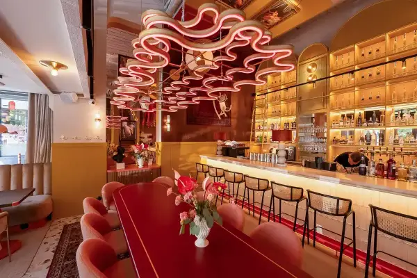 Eleganckie restauracje Kołobrzeg: czerwony stół, różowe fotele i bar z alkoholem.