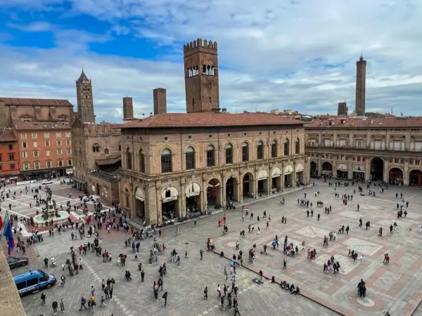 Tłum ludzi na Piazza Maggiore w Bolonii, podziwiający zabytkowe budynki i wieże. To serce miasta i jego główne bolonia atrakcje.