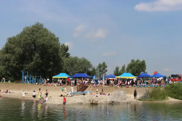 Ludzie odpoczywają nad wodą, pod namiotami odbywają się zawody. To piękne jeziora na Podkarpaciu w słoneczny dzień.