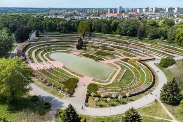 Widok z lotu ptaka na park cytadela z jeziorem, tarasami i alejkami. W tle widać miasto.