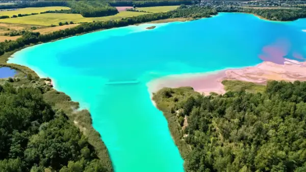 Turkusowe jezioro otoczone zielenią, przypominające polskie Malediwy. Piaskowe plaże i bujna roślinność tworzą malowniczy krajobraz.