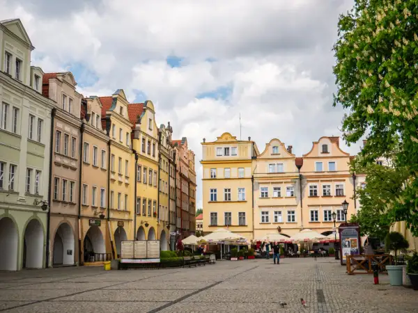 Kolorowe kamienice na rynku, kawiarniane stoliki i drzewa tworzą urokliwy widok. To idealne miejsce, by odkrywać **Jelenia Góra atrakcje**.