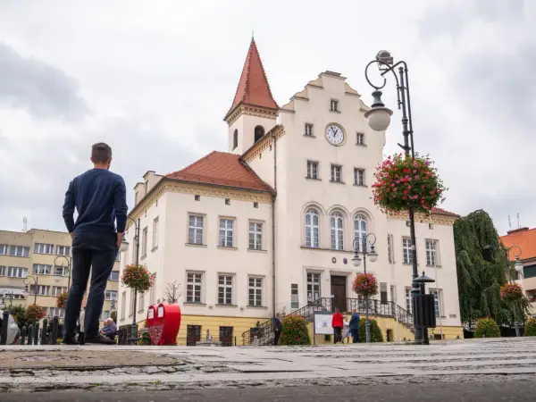 Mężczyzna patrzy na ratusz w Trzebnicy, jedno z wielu urokliwych miejsc i atrakcji tego miasta.