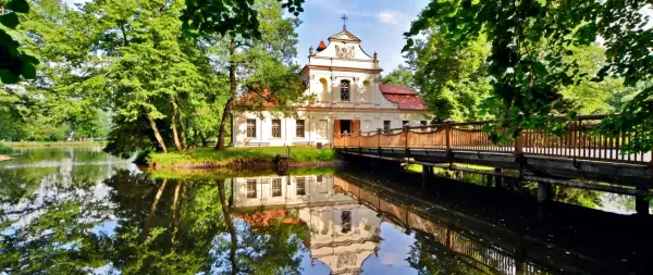 Pałac z mostkiem i odbiciem w wodzie. Wspaniałe zwierzyniec atrakcje czekają na zwiedzających w otoczeniu zieleni.