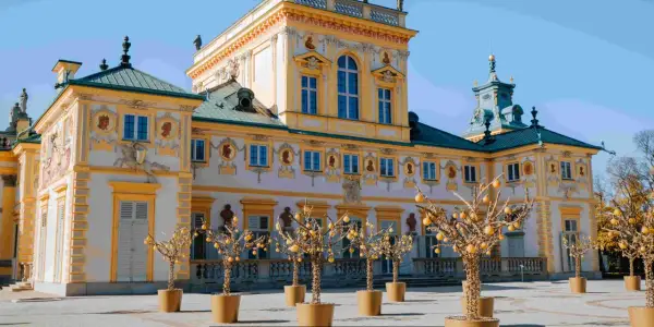 Barokowy pałac, jeden z pięknych muzeów w Polsce, z ozdobnymi drzewkami w donicach przed fasadą.