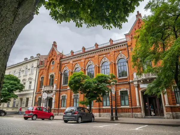 Kamienice w Radomiu, w tym Bank Polski, to ciekawe atrakcje. Dwa samochody stoją przed budynkami.