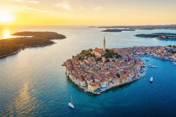 Zachód słońca nad malowniczym Rovinj w Chorwacji. Miasto z charakterystyczną wieżą kościelną, otoczone turkusowym morzem i zielonymi wyspami.