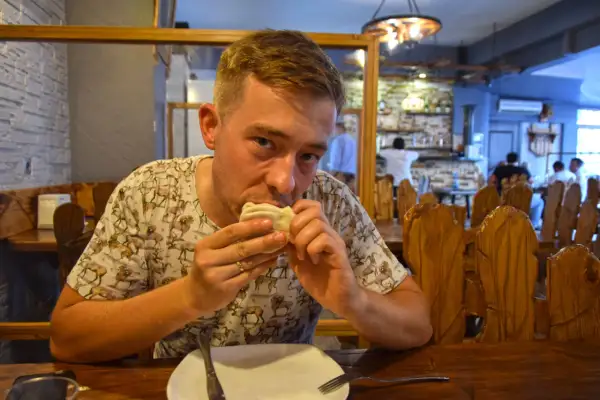 Mężczyzna je pierożki, delektując się smakami kuchni gruzińskiej w przytulnej restauracji.