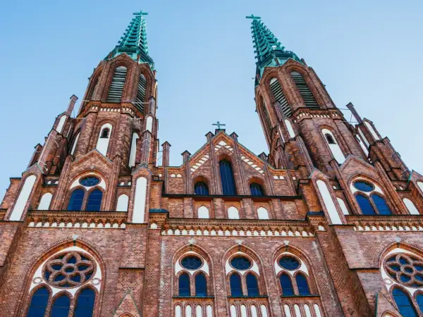 Imponująca ceglana bazylika z dwiema strzelistymi wieżami, ozdobiona oknami i detalami architektonicznymi. Jeden z najpiękniejszych kościołów w Polsce.