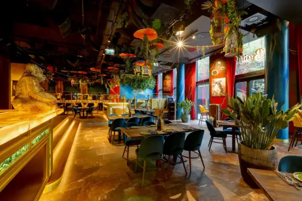 Złota małpa wita w jednej z klimatycznych restauracji Warszawa. Wnętrze pełne zieleni, czerwonych zasłon i egzotycznych dekoracji.