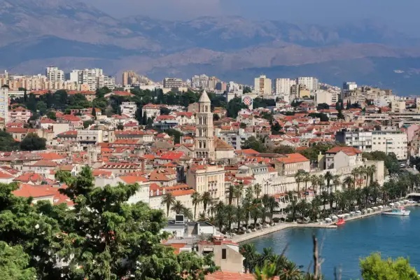 Widok na miasto Split z palmami i morzem. W oddali góry. Mnóstwo atrakcji turystycznych czeka na odkrycie.